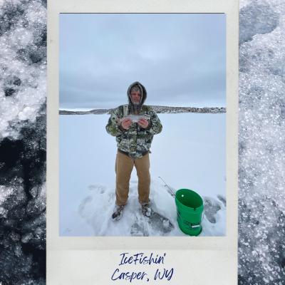 "Image of Justin Putzier, The Outdoorsman REALTOR® from The Putzier Real Estate Team at House Real Estate Group, holding a brown trout while ice fishing at Alcova Reservoir in Wyoming. The background shows frozen water and a snowy landscape, with a few trees in the distance."